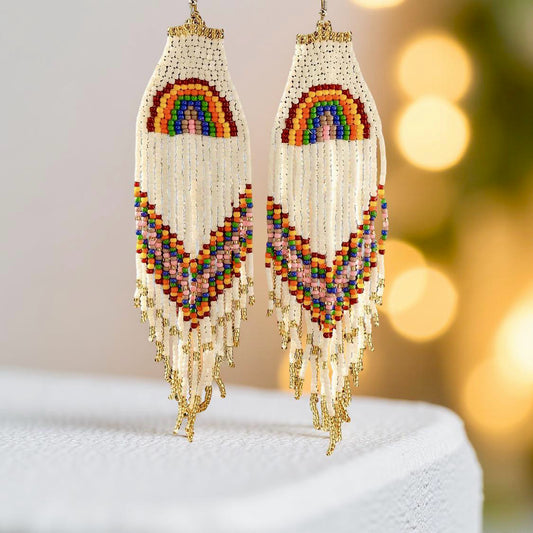 Handmade beaded earrings with a rainbow design at the top and long fringe, featuring colourful beads in red, yellow, green, blue, and purple. The earrings are finished with hypoallergenic 316L surgical steel lever backs.