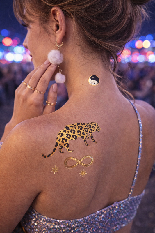 Kundalini metallic gold and black temporary tattoos glowing under flash at night festival