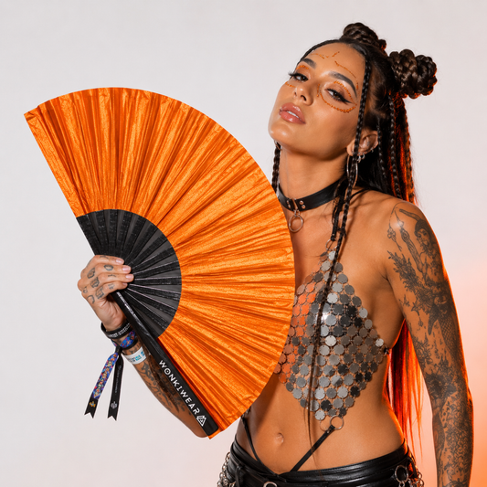 Festival model holding XL orange shimmer metallic festival fan during studio photoshoot