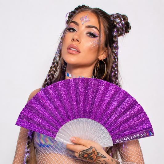 Female festival model holding small purple glitter folding fan at music festival