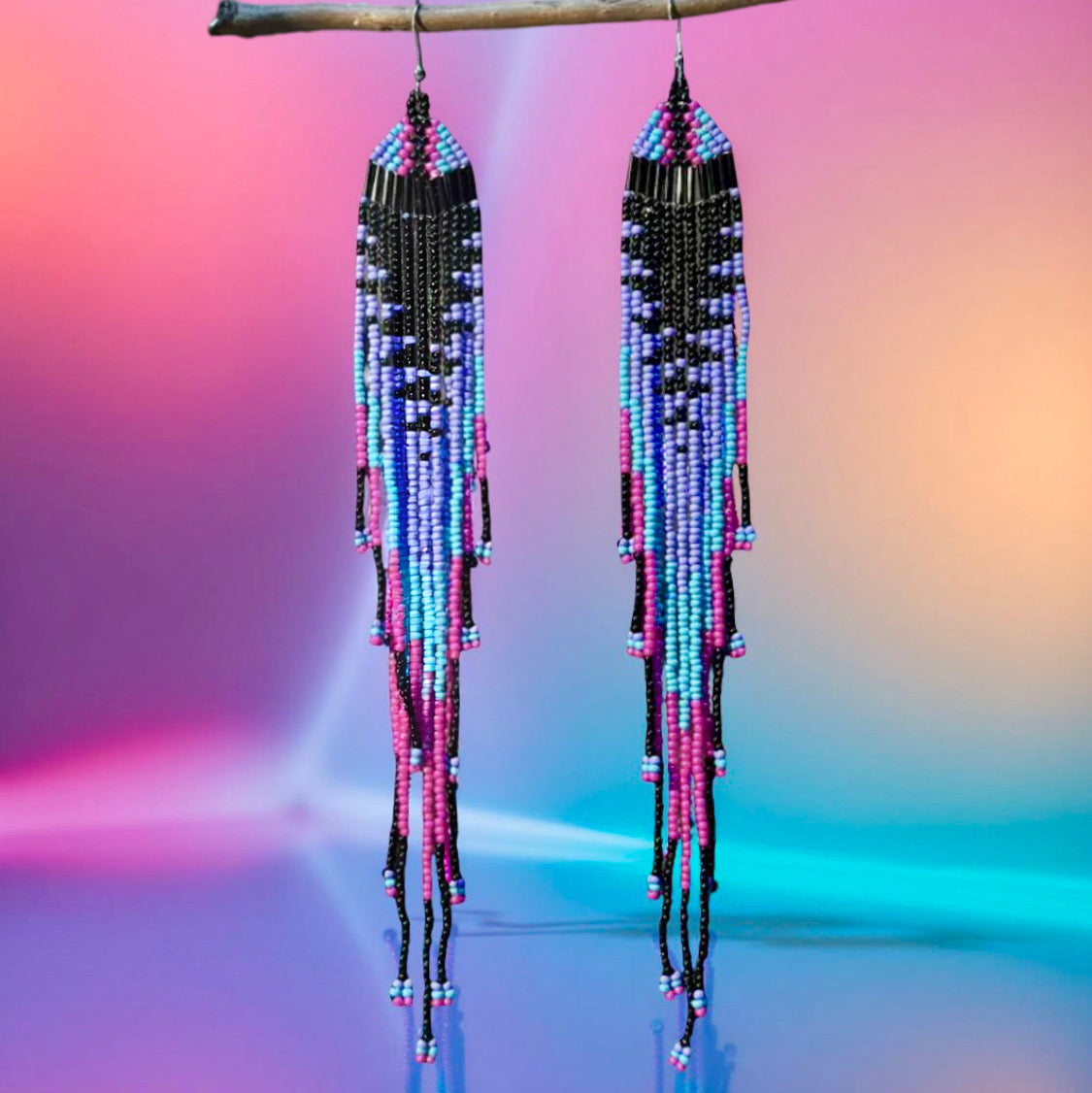 Long beaded earrings with colourful seed beads imitating a jellyfish in front of an illuminated neon background 