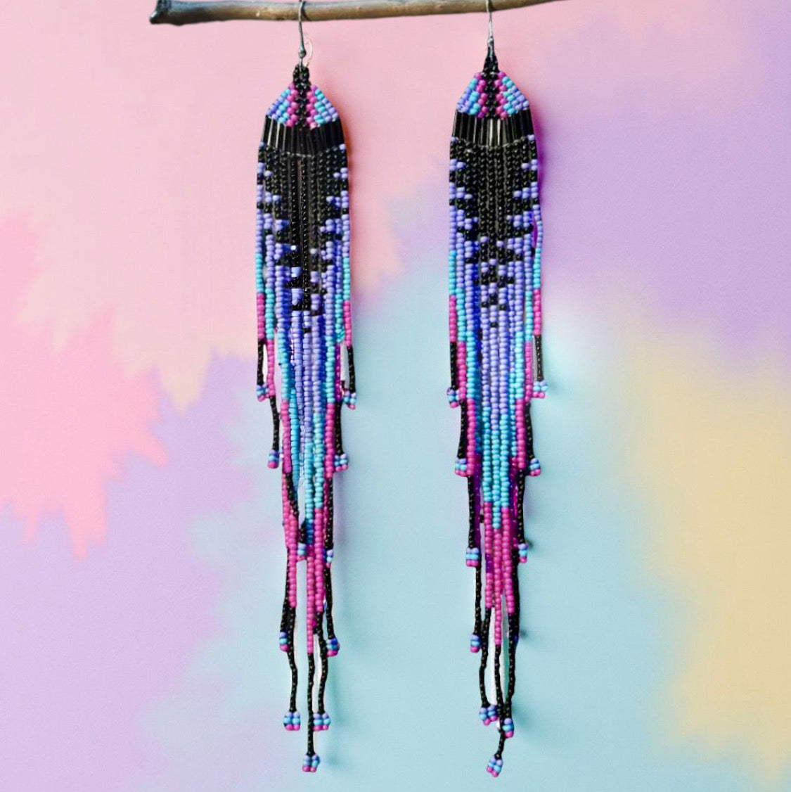 Long beaded earrings with colourful seed beads imitating a jellyfish in front of a pastel background 