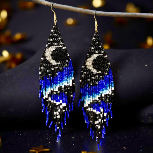 Handmade beaded earrings with a crescent moon design at the top and long black, blue, and white beaded fringe, finished with hypoallergenic 316L surgical steel lever back hooks.