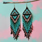 Handmade beaded earrings featuring turquoise and pink long tassel fringe, with hypoallergenic medical-grade 316L surgical steel lever backs, in front of a pastel background 