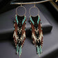 Handmade beaded earrings featuring a hoop and long fringe, with turquoise, brown, black, and cream beads. The earrings are finished with hypoallergenic 316L surgical steel lever backs.