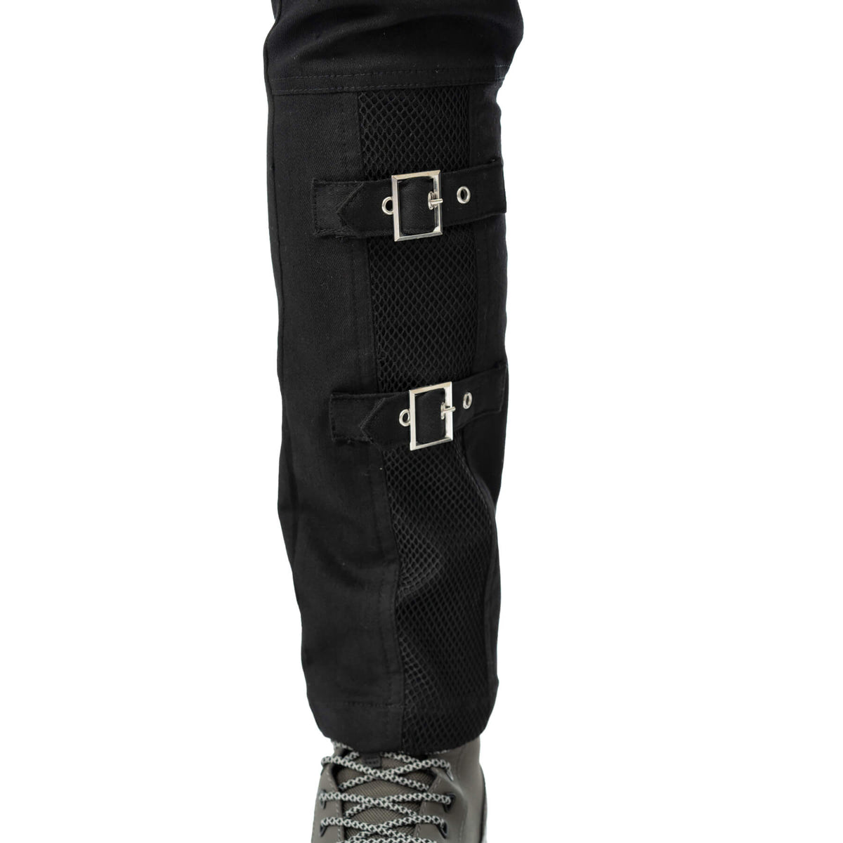Close-up of the decorative buckle straps on the lower leg of the black trousers