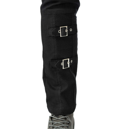 Close-up of the decorative buckle straps on the lower leg of the black trousers