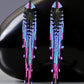 Long beaded earrings with colourful seed beads imitating a jellyfish in front of a shiny black surface