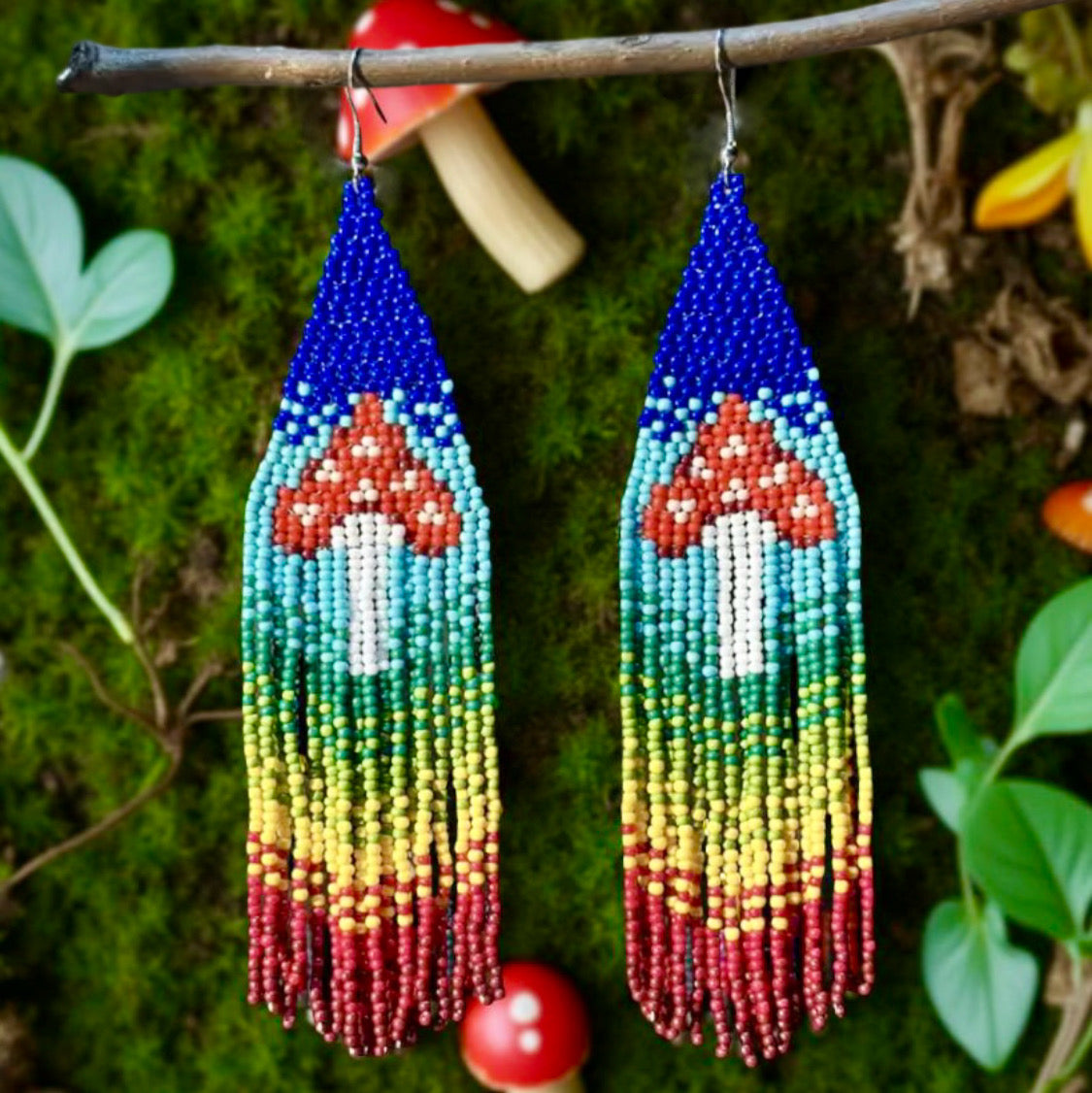 Handmade beaded earrings with a colourful rainbow fringe and red-and-white mushroom design, finished with hypoallergenic surgical steel Leverbacks