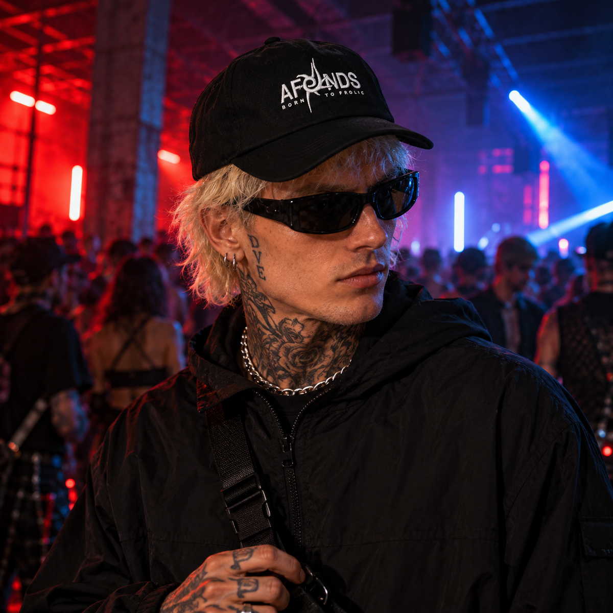 Black AFENDS Antic cap styled with an alternative streetwear look at an underground UK rave, with dramatic red and blue warehouse lighting.