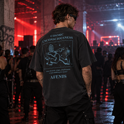 AFENDS Cosmic Unconsciousness charcoal graphic T-shirt shown from the back on a male raver at an underground warehouse rave with red and blue lighting.