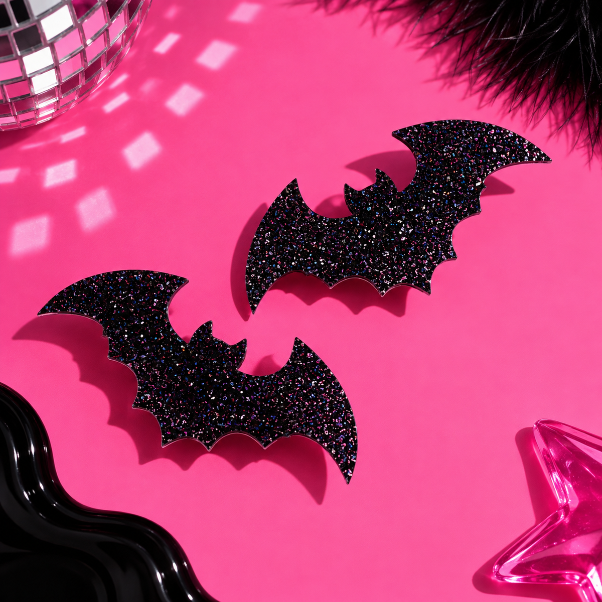 Set of two black glitter bat hair clips by Cuteryko on a bright pink background