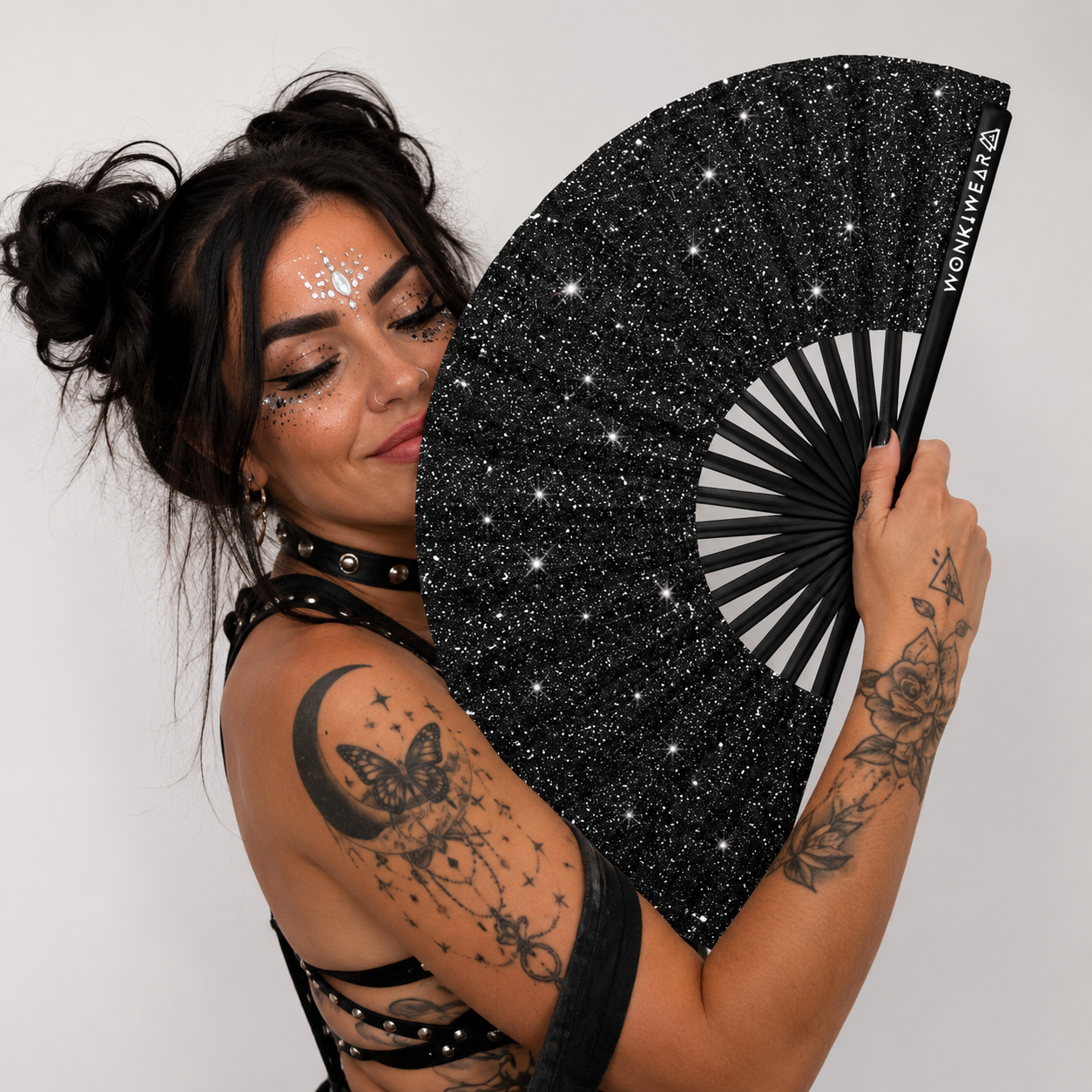 Female raver wearing black glitter leg holster and holding black glitter festival fan