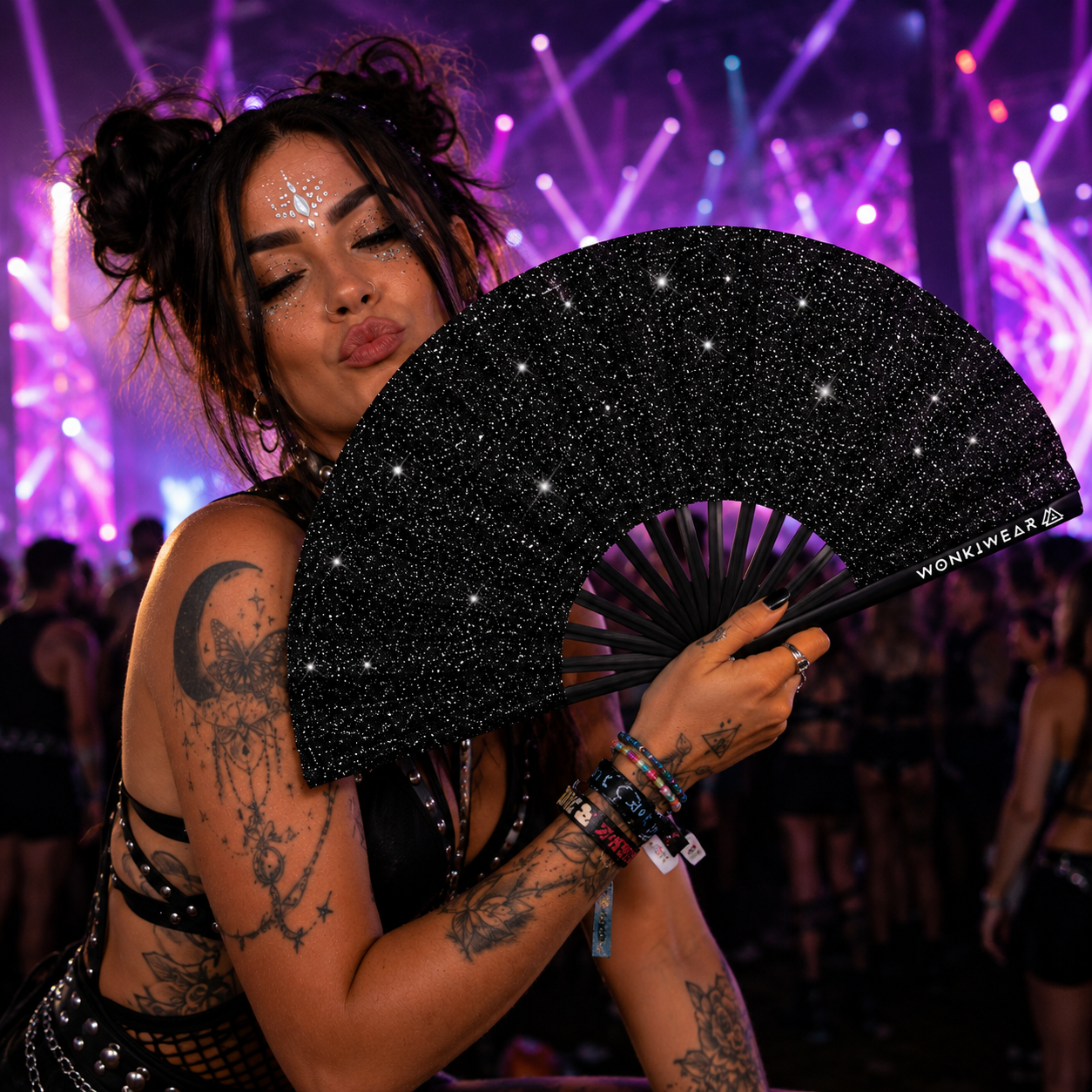 Female raver wearing black glitter leg holster and holding black glitter festival fan at a rave
