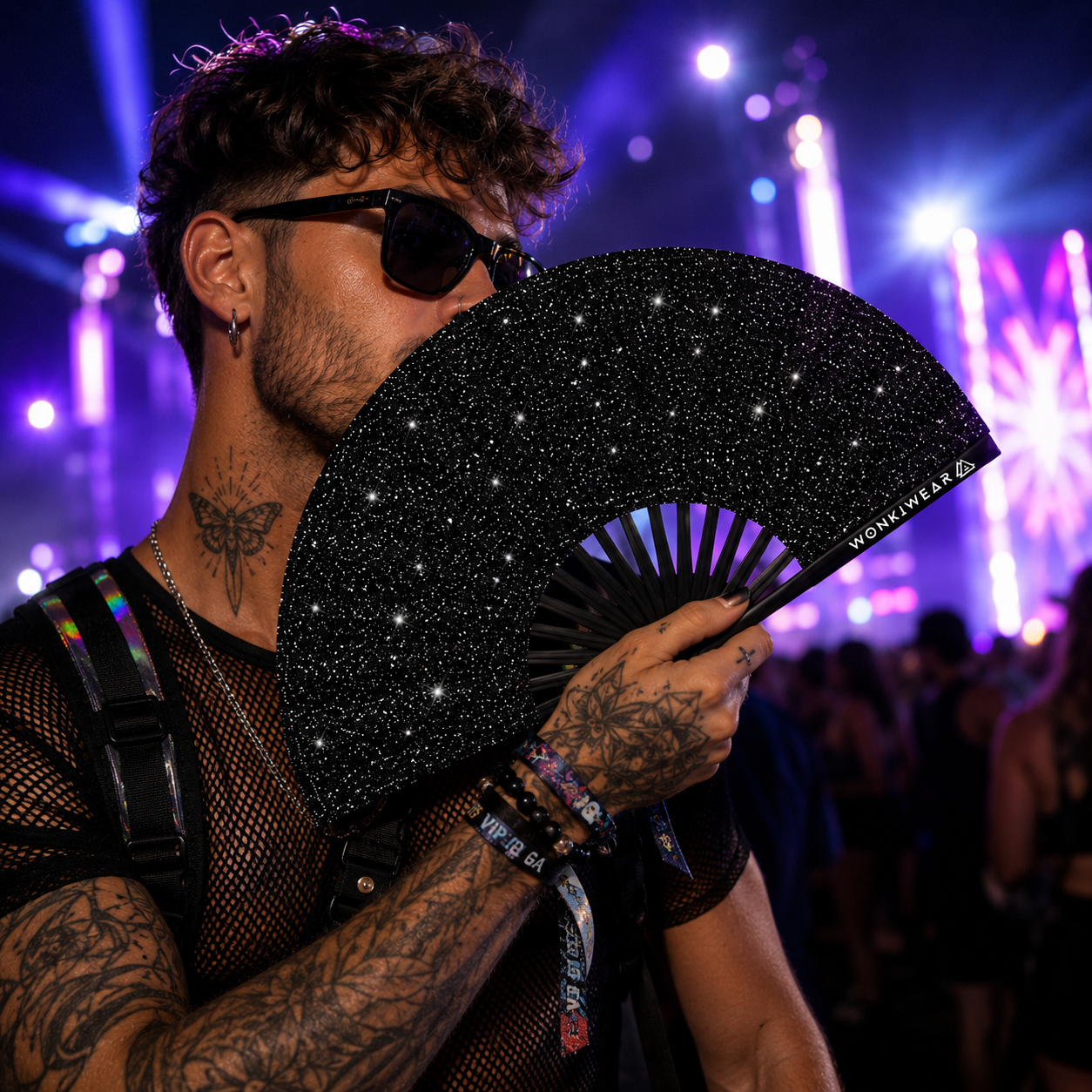Male festival model wearing black glitter fan holster and holding black glitter rave fan