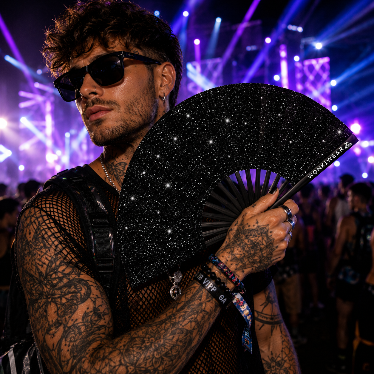 Male rave model holding black glitter folding fan at music festival