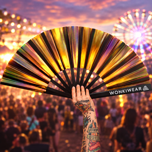 Bronze iridescent festival fan held up against a colourful sunset rave crowd with a ferris wheel in the background