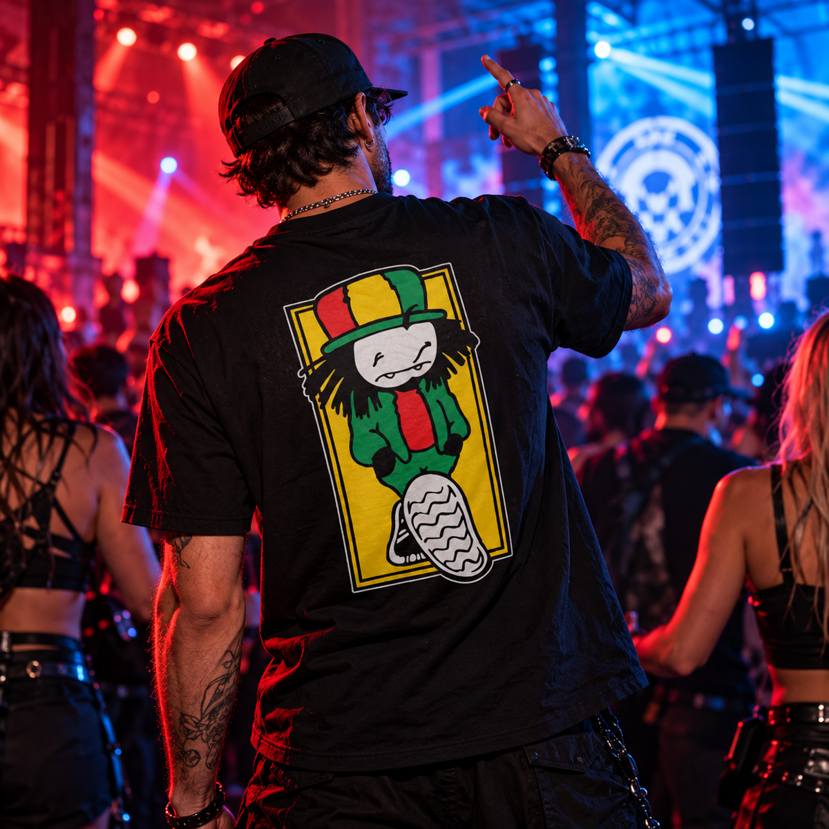 Man wearing the black Dready graphic T-shirt, showcasing the large colourful back print, at an underground drum and bass rave with red and blue warehouse lighting.