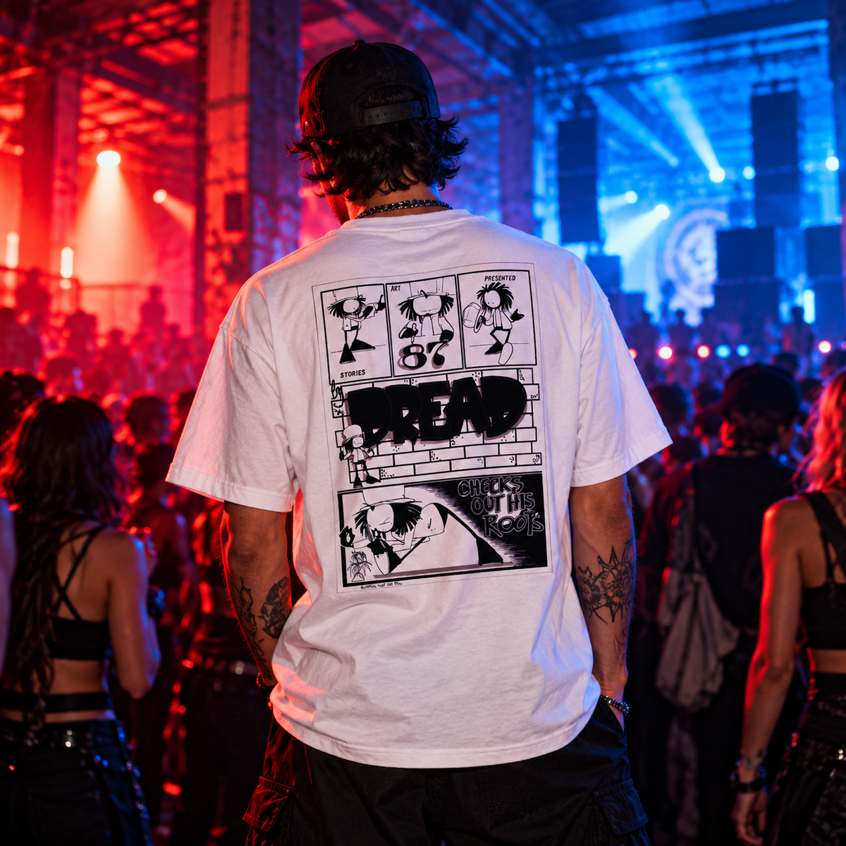 Man wearing the white Dready Walking Dread graphic T-shirt, showcasing its bold comic-style back print, at an underground drum and bass rave with red and blue warehouse lighting.