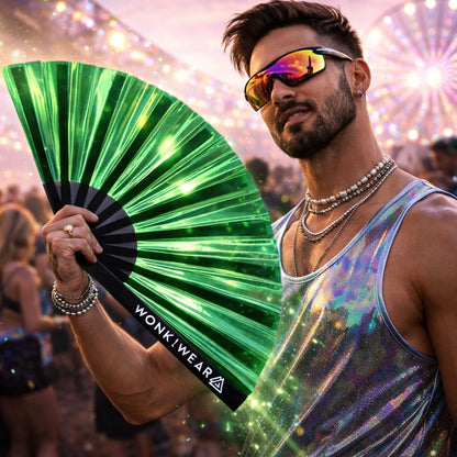 Male festival goer holding emerald iridescent rave fan wearing reflective outfit