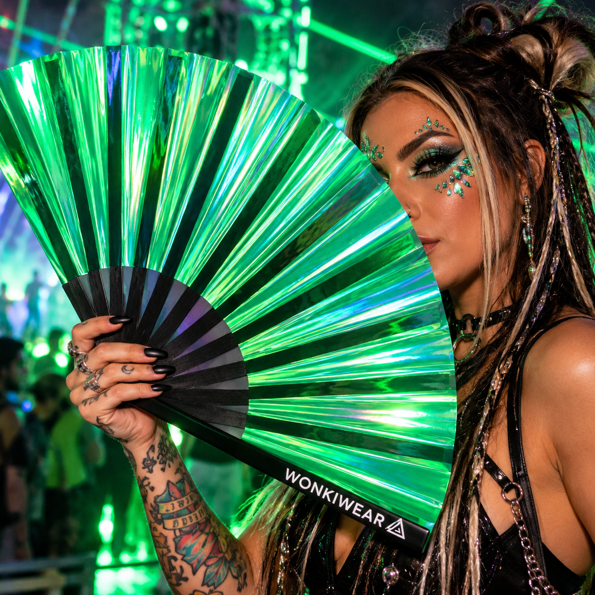 Woman holding an emerald green iridescent XL festival fan at a neon rave