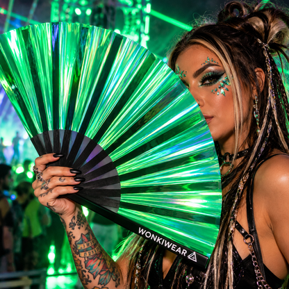 Woman holding an emerald green iridescent XL festival fan at a neon rave