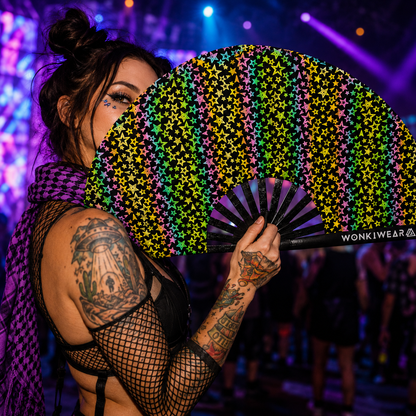 Person holding reflective stars festival fan under colourful rave lighting
