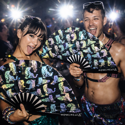 Festival couple holding rainbow reflective tiger rave fans glowing under flash photography at a rave