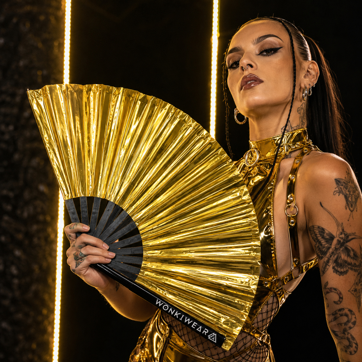 Festival model using oversized metallic gold rave fan