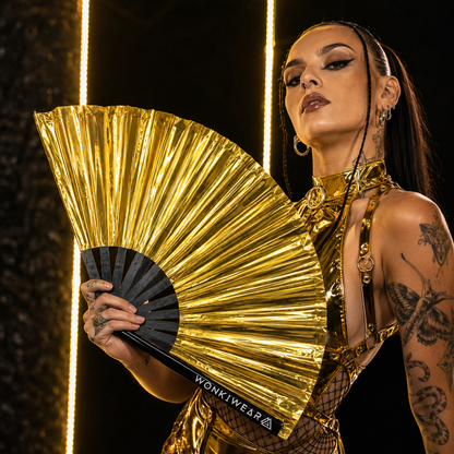 Festival model using oversized metallic gold rave fan