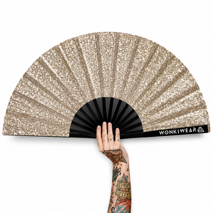 Gold glitter folding festival fan with tattooed hand on white background