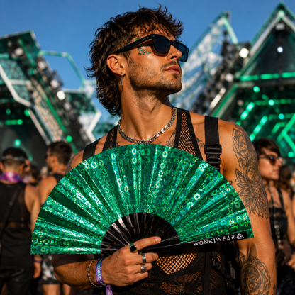 Male festival goer holding green holographic XL rave fan