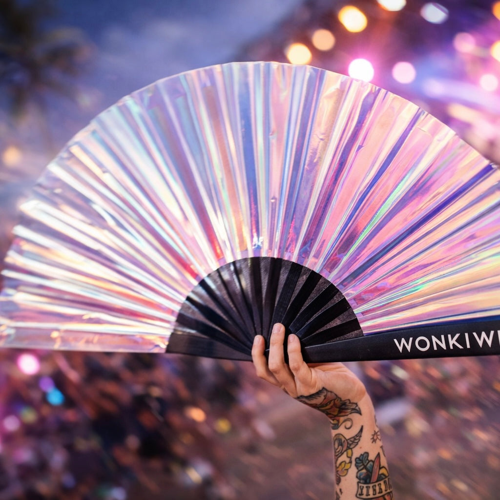 Person holding iridescent festival fan at rave with colourful lights and crowd background