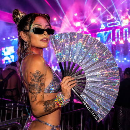 Festival attendee using Mirror Maze holographic rave fan under festival lights