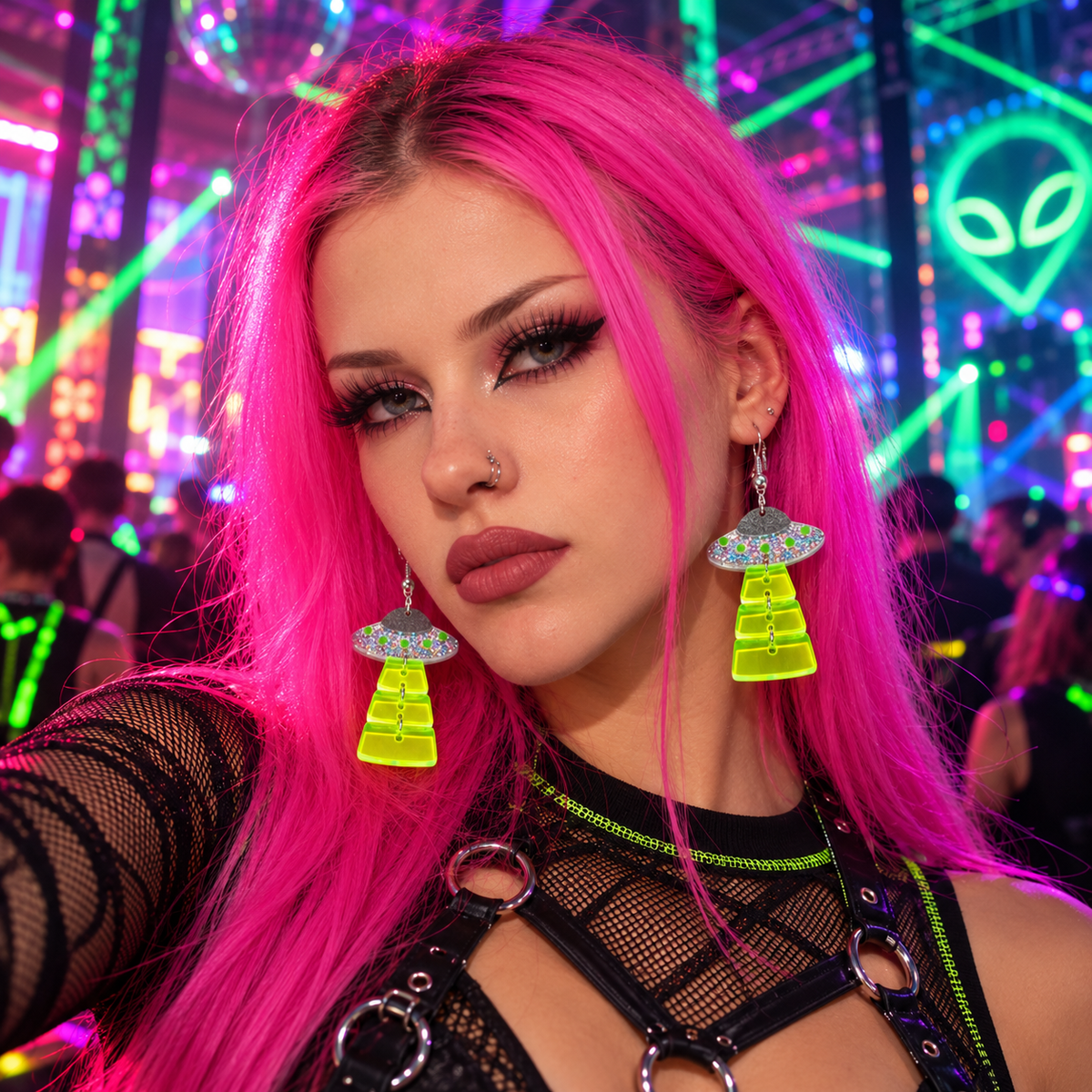 Woman with bright pink hair wearing neon UFO glitter drop earrings at a colourful rave