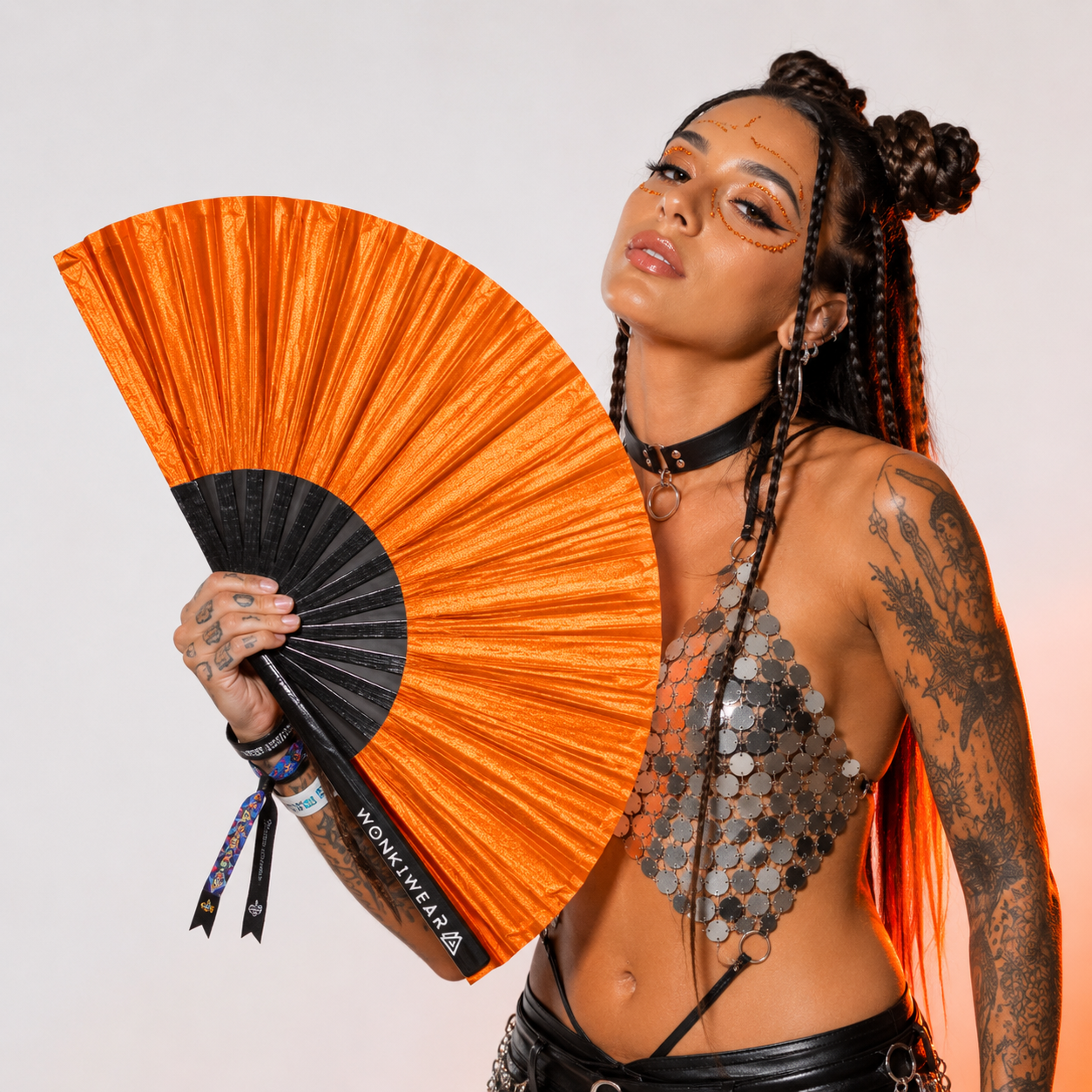 Festival model holding XL orange shimmer metallic festival fan during studio photoshoot