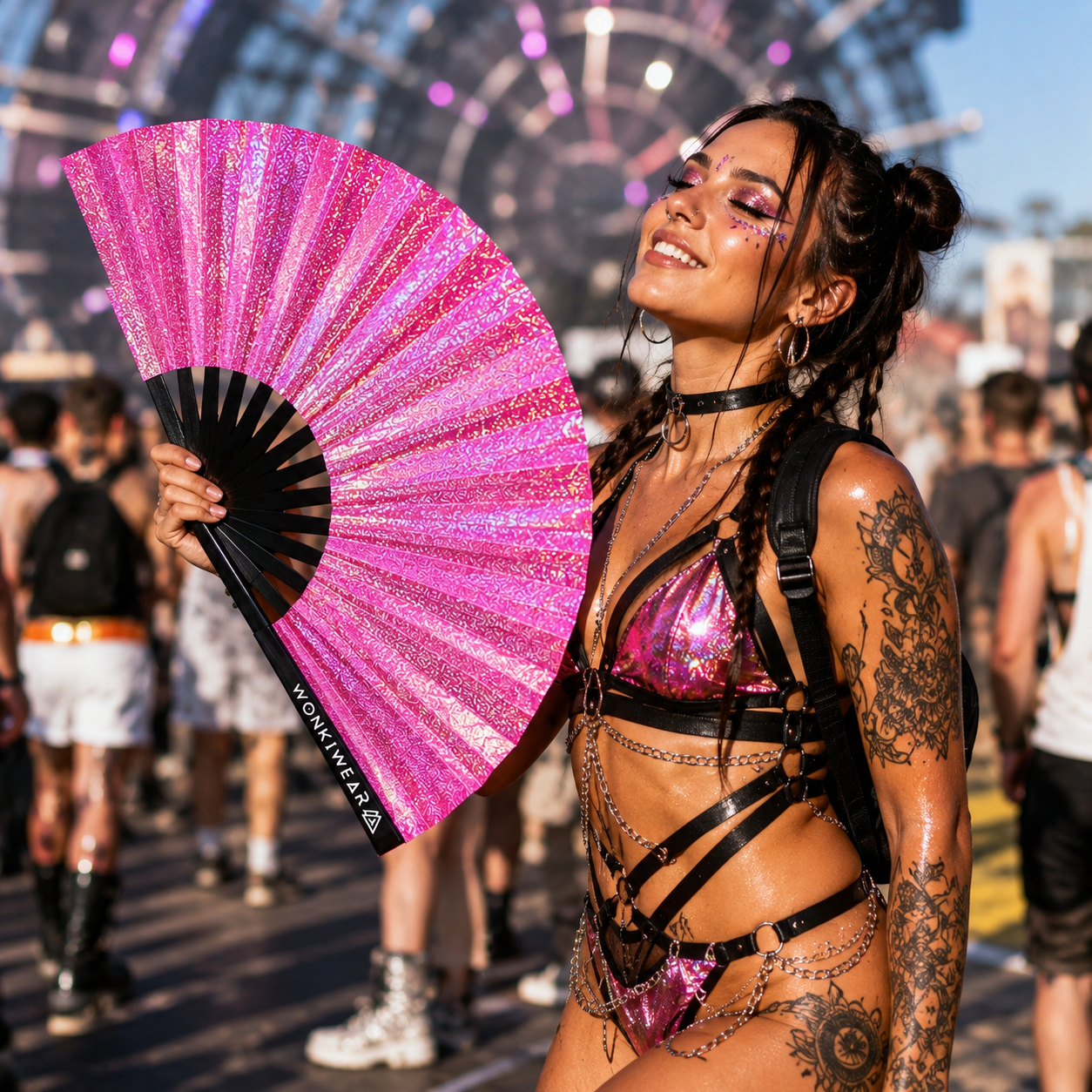 Festival attendee using Orion Galaxy holographic pink festival fan outdoors