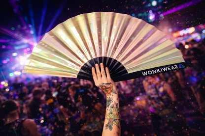 Pearl iridescent festival fan held in a crowd at night, glowing under lights at a rave
