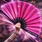 Pink holographic festival fan in motion with light reflections at a rave