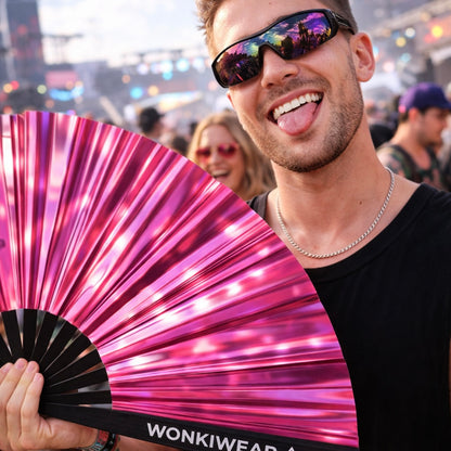 Man holding Pink Mirage metallic pink rave fan at festival with reflective iridescent finish