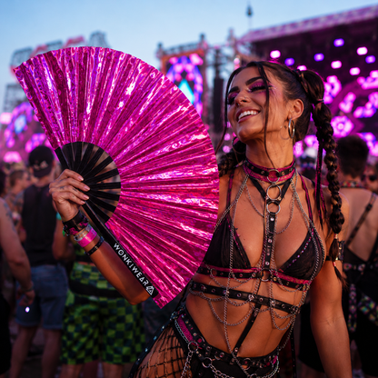 Festival attendee using Pink Pulse holographic fan at outdoor music festival