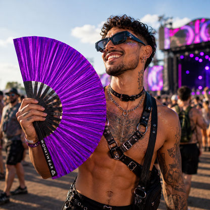Male festival attendee holding XL purple shimmer festival fan at summer event