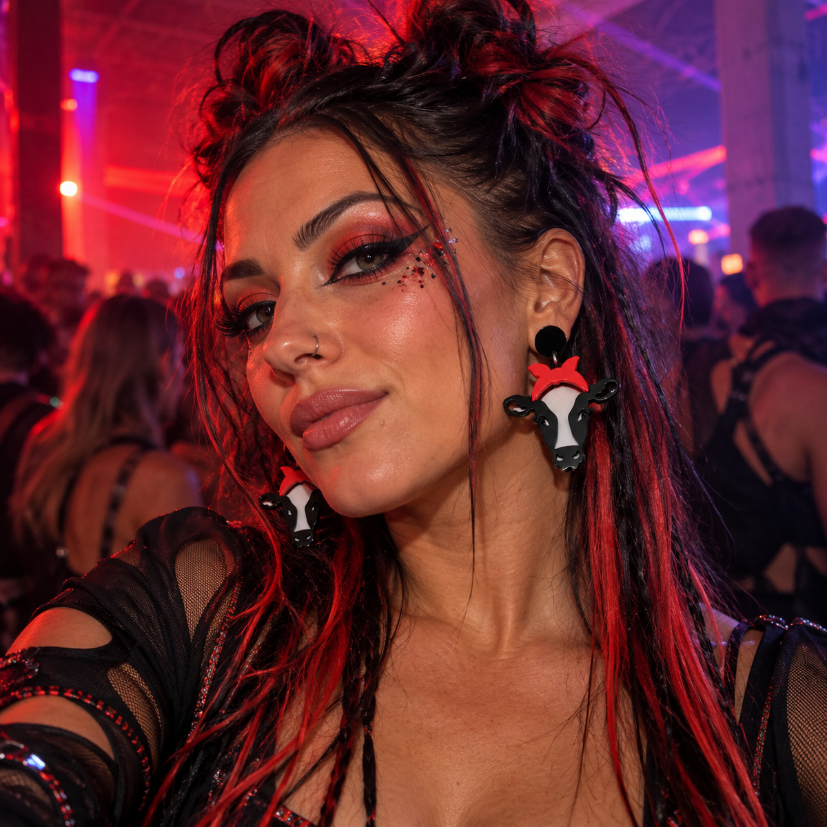Woman wearing red and black cow statement earrings at a neon warehouse rave