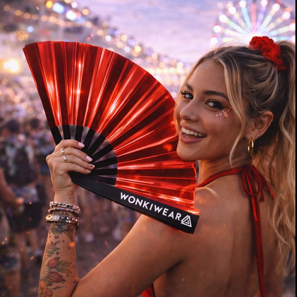 Woman holding red iridescent festival fan with glitter makeup at rave