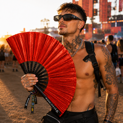 Male festival attendee using XL red shimmer festival fan at outdoor event