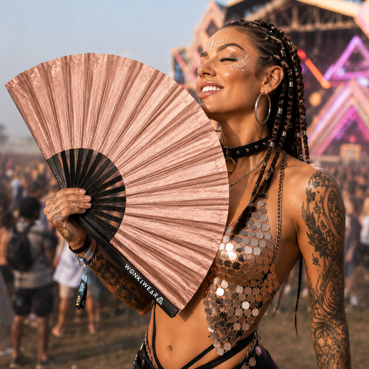 Festival goer using rose gold shimmer festival fan outdoors at music festival