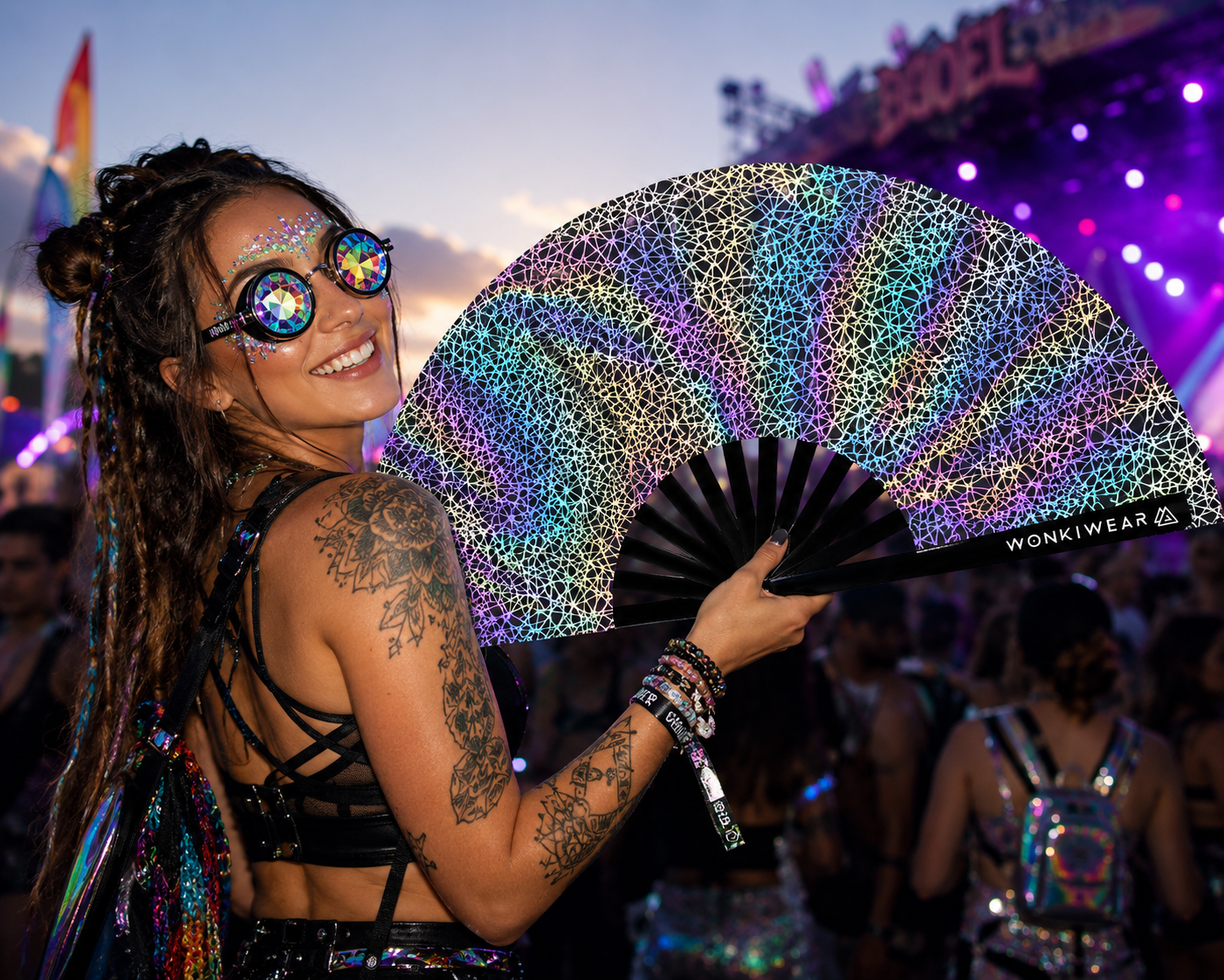 Person holding WonkiWear silver web reflective festival fan in rave crowd under colourful lights