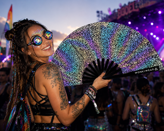 Person holding WonkiWear silver web reflective festival fan in rave crowd under colourful lights