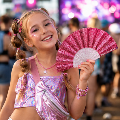 Child using light pink glitter folding fan at outdoor festival