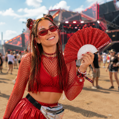Woman using red glitter folding fan at outdoor music festival
